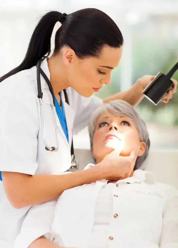 Dermatologist examining an elderly patient’s facial skin with a diagnostic light