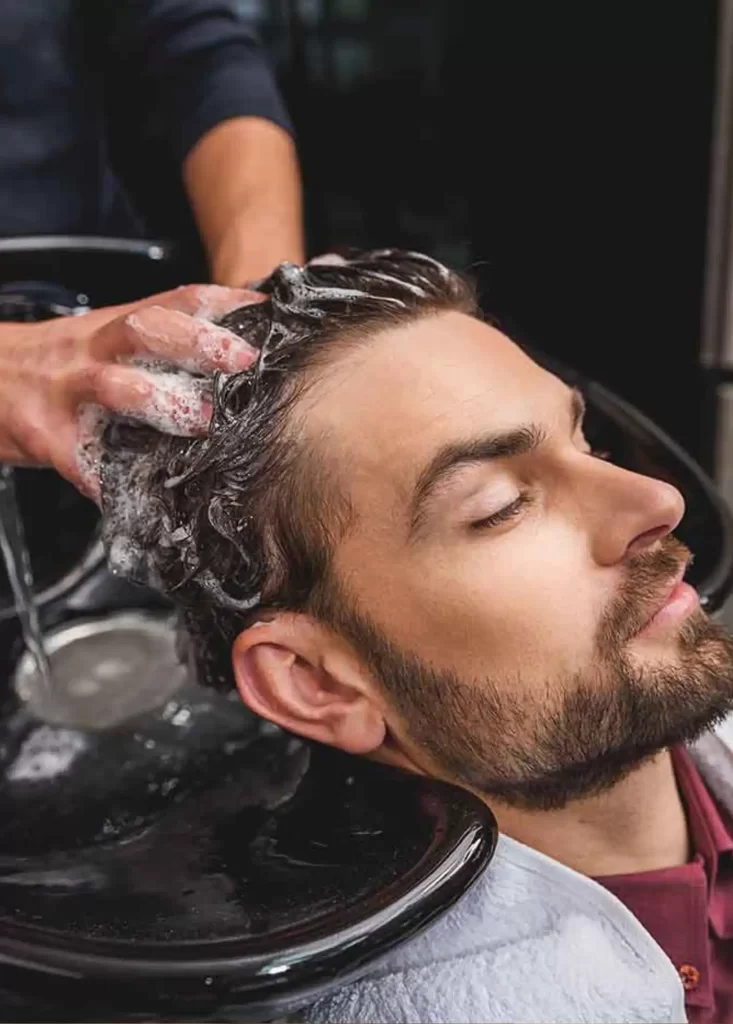 Man receiving a professional hair wash and scalp cleansing treatment at Emara Skin Clinic