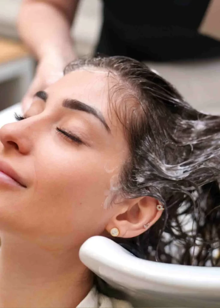 Woman receiving a relaxing hair wash and scalp cleansing treatment at a clinic