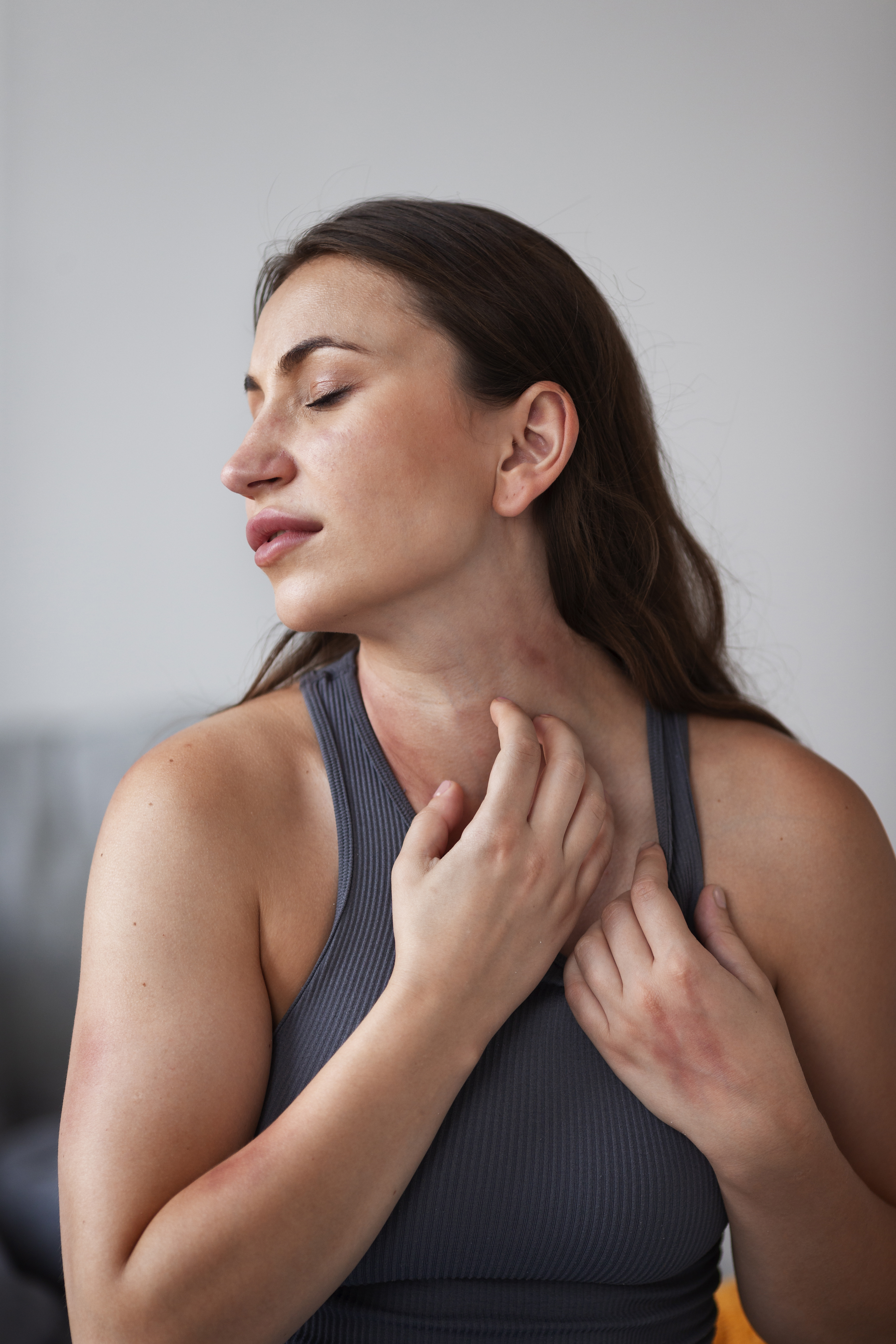 Woman scratching neck due to eczema irritation – eczema treatment at Emara Skin Care